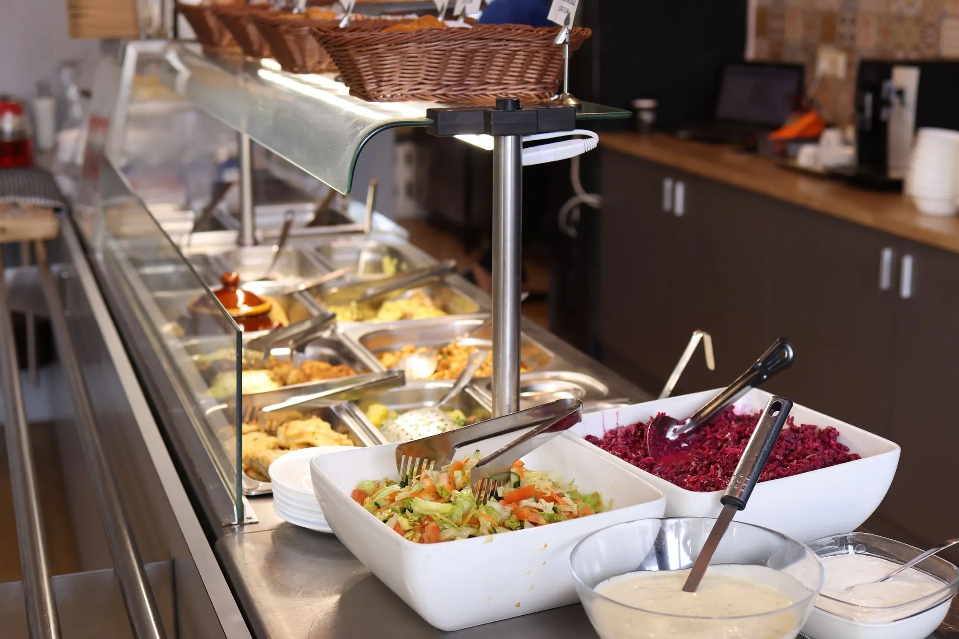 Línea de servicio de un comedor con bandejas de comida y ensaladas