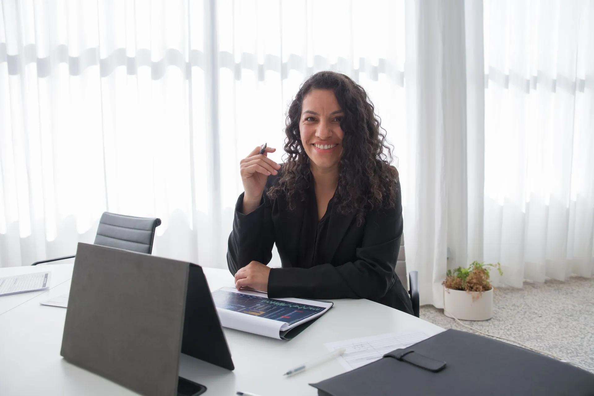 Ejecutiva de ventas sonriente en su escritorio con un reporte de resultados